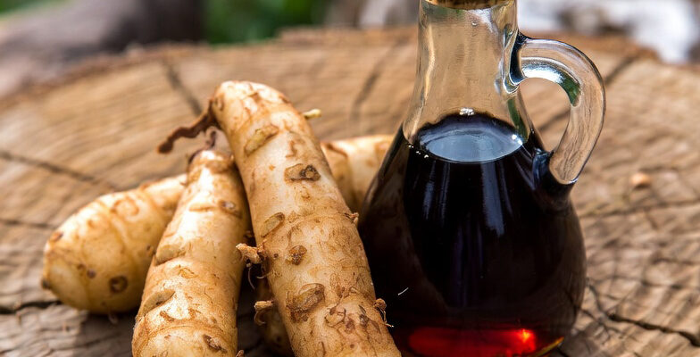 Yacon Wurzeln auf ein Holz Baum mit ein Sirup von Yacon im Glass